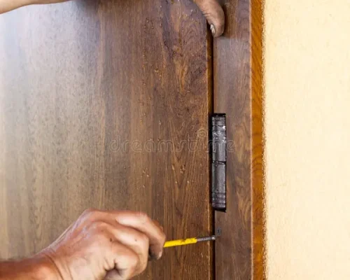 front-door-installation-worker-fastens-door-trims-screwdriver-90098030